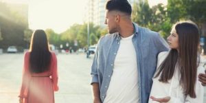 A man in a formal outfit, presumably with his partner, distractedly gazing at a woman passing by.